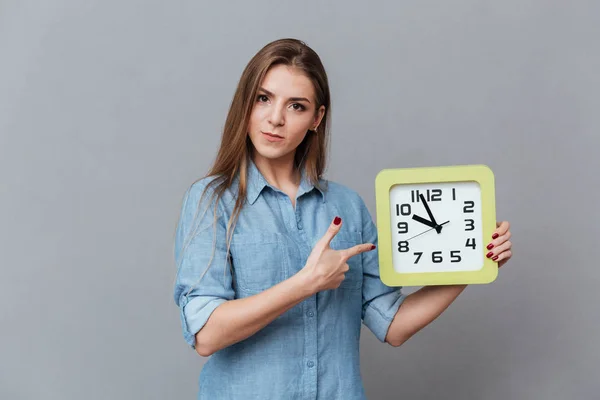 Mujer seria en camisa sosteniendo reloj — Foto de Stock