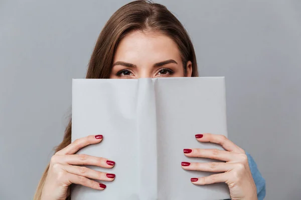 Vrouw in hemd verstopt achter het boek — Stockfoto