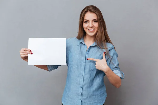 Woman in shirt pointing on blank board — Stock Photo, Image