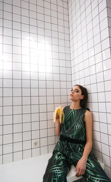 Mulher sentada na mesa e comendo banana no café — Fotografia de Stock