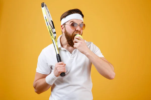 Éhes fiatal játékos harap tenisz labda. — Stock Fotó