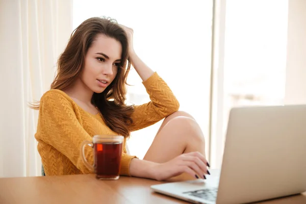 Mujer atractiva joven en suéter que trabaja con el ordenador portátil en casa — Foto de Stock