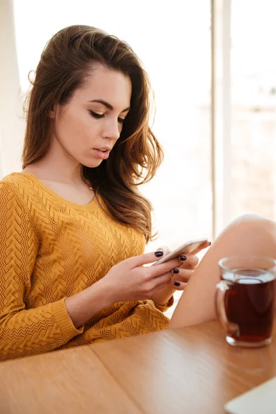 Привлекательная молодая женщина читает сообщения на мобильном телефоне — стоковое фото