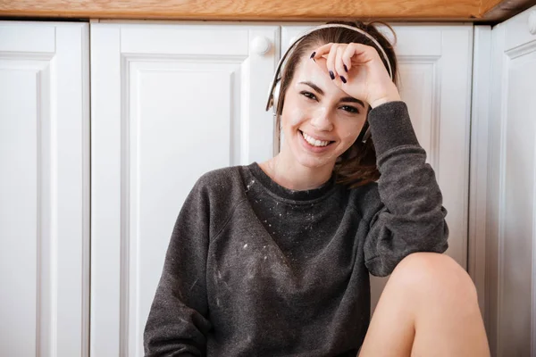 Kvinna som lyssnar på musik med hörlurar i köket — Stockfoto