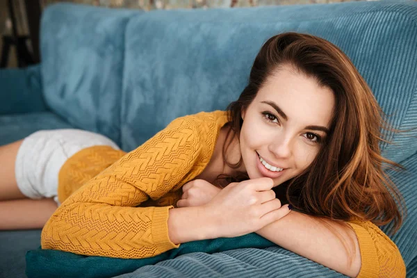 Sonriente chica descansando en un sofá y mirando a la cámara —  Fotos de Stock