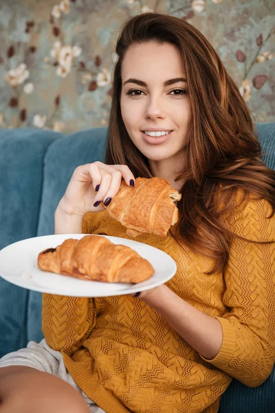 Portret van een lachende aantrekkelijke vrouw eten croissant — Stockfoto