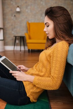 Tablet pc ile katta oturan genç kız gülümseyerek