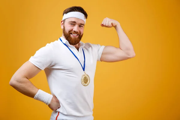 Glücklicher junger Sportler mit Medaille, der seinen Bizeps zeigt. — Stockfoto