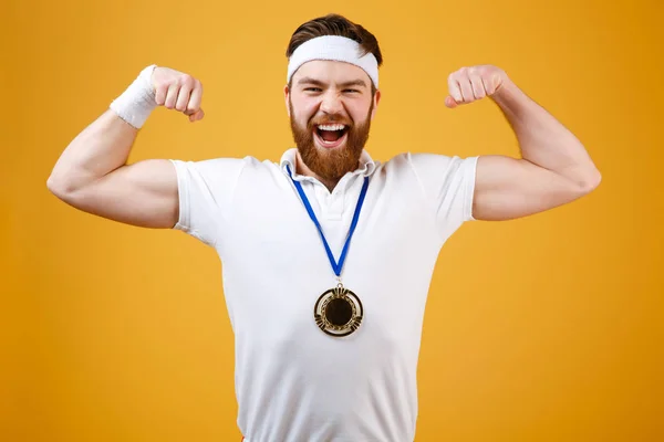 Jeune sportif émotionnel avec médaille montrant ses biceps — Photo
