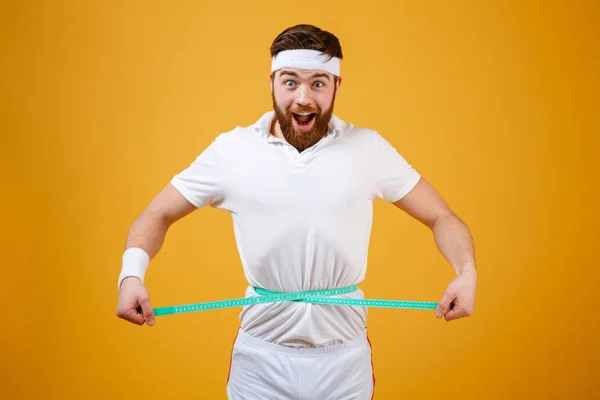 Feliz barbudo de fitness midiendo su cintura con cinta adhesiva —  Fotos de Stock