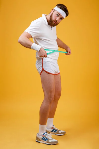 Retrato de cuerpo entero de un hombre frustrado midiendo su cintura — Foto de Stock