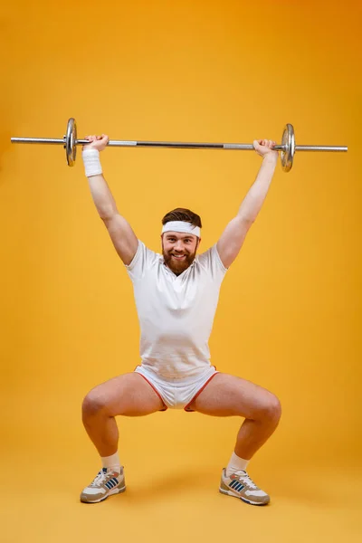 Полная длина спортивного человека, делающего упражнения на корточках с штангой — стоковое фото