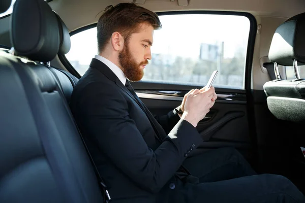 Vista lateral del hombre de negocios barbudo con teléfono inteligente —  Fotos de Stock