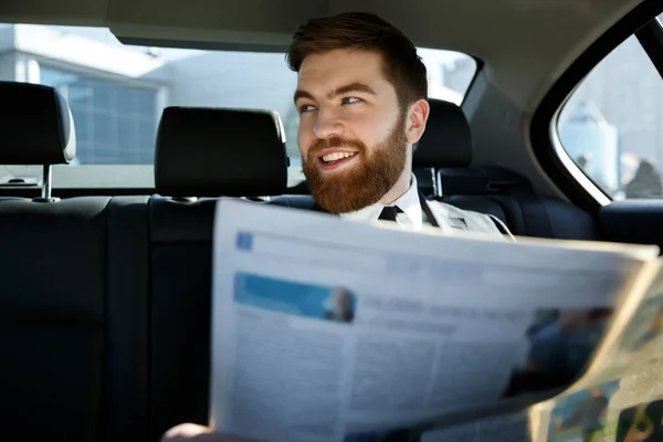 Gazete ile oturan mutlu sakallı adam — Stok fotoğraf