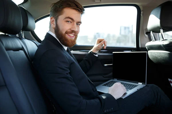 Vista lateral del hombre de negocios sonriente con portátil —  Fotos de Stock