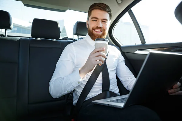 Leende affärsman med laptop hålla kopp kaffe — Stockfoto