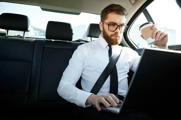 Seriös affärsman med laptop och innehav kopp kaffe — Stockfoto