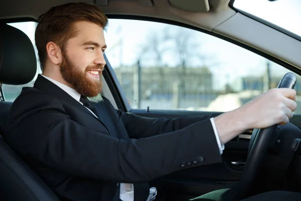 Side view of smiling business man sitting at the wheel — Stock Photo, Image