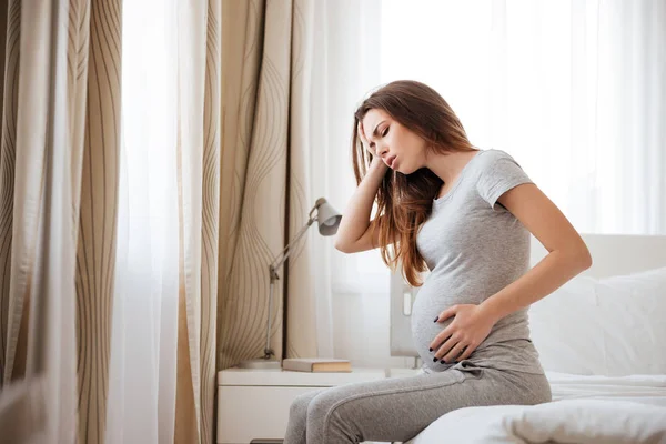 Traurige Schwangere mit Kopfschmerzen und Übelkeit im Bett — Stockfoto