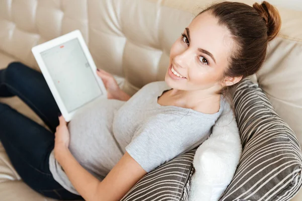 ソファーに空白の画面のタブレットを使用して陽気な妊娠中の若い女性 — ストック写真
