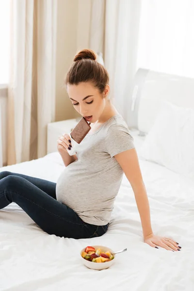 Schwangere hat die Wahl zwischen Schokoriegel und Obstsalat — Stockfoto