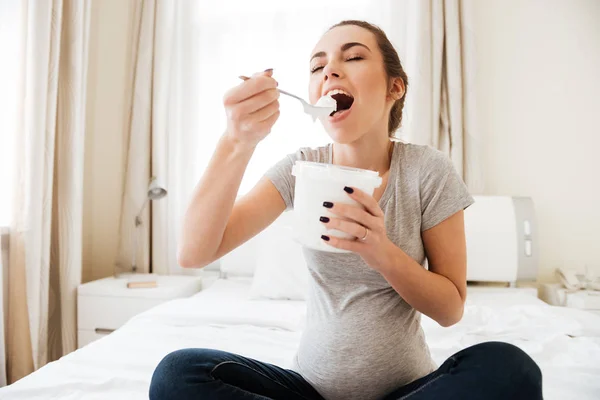 Joven embarazada alegre sentada y comiendo helado —  Fotos de Stock