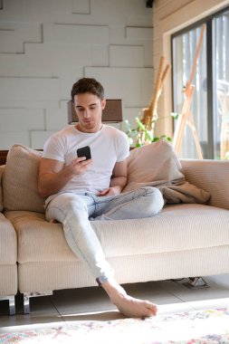 Telefon ile kanepede oturan adam