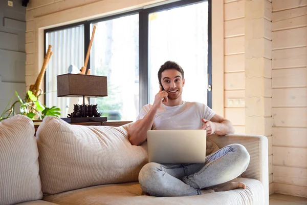 Hombre con teléfono y portátil en casa — Foto de Stock