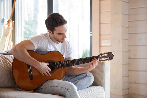 소파에 앉아 기타를 가진 남자 — 스톡 사진
