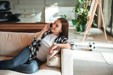 Kadın gülümsüyor ve telefonda konuşuyor.