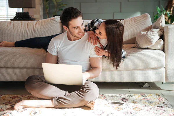 Hombre sentado con el ordenador portátil y su mujer en casa — Foto de Stock