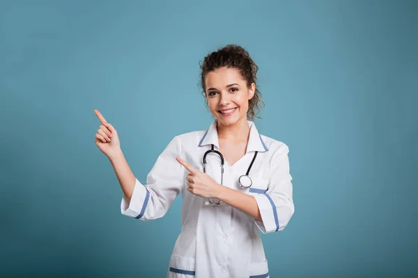 Gelukkig jonge verpleegster met de stethoscoop wijzen — Stockfoto