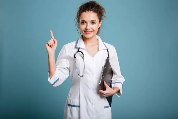 Médecin en manteau blanc avec stéthoscope et presse-papiers pointant du doigt — Photo