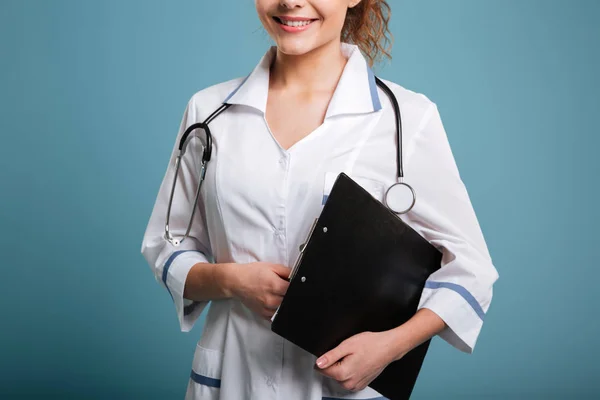 Sonriente linda doctora o enfermera sujetando portapapeles — Foto de Stock
