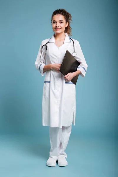 Lächelnde freundliche Krankenschwester mit Klemmbrett und Blick in die Kamera — Stockfoto