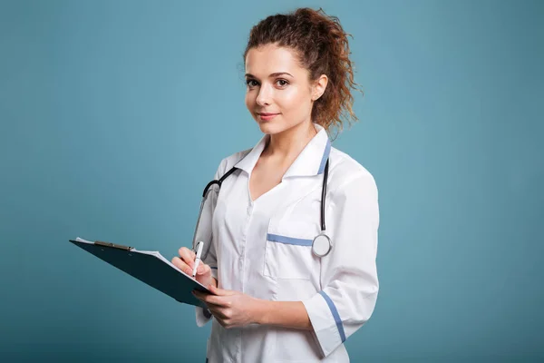 Potret bahagia tersenyum perempuan dokter menulis di papan klip — Stok Foto