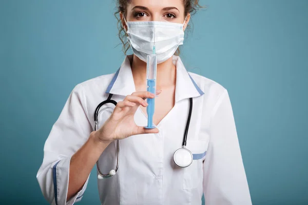 Medico in maschera sirgica mostrando siringa — Foto Stock