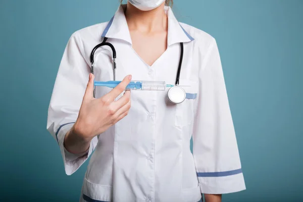 Donna medico im maschera mostrando siringa — Foto Stock