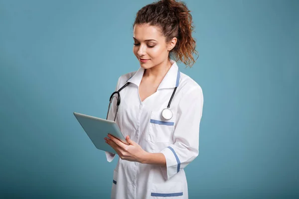 Улыбающаяся женщина-врач или медсестра с помощью планшетного компьютера — стоковое фото