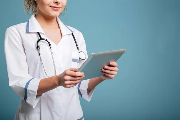 Sonriente joven doctora con uniforme sosteniendo la tableta de la PC — Foto de Stock