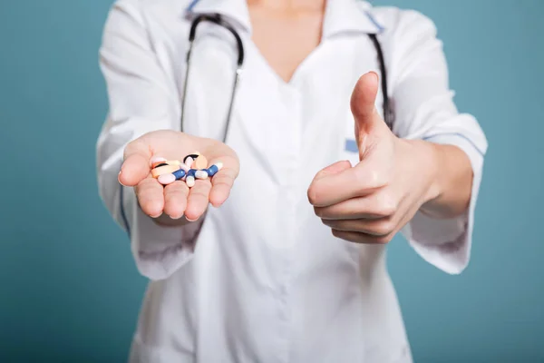 Tiro de mostrar pílulas na mão de enfermeira e polegar para cima — Fotografia de Stock
