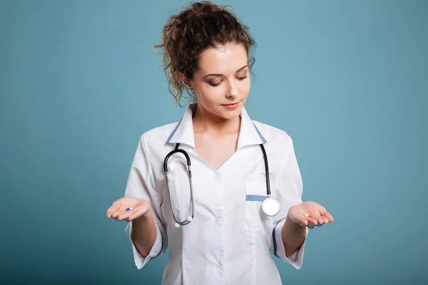 Enfermeira mulher fazendo escolha entre pílulas em sua mão — Fotografia de Stock