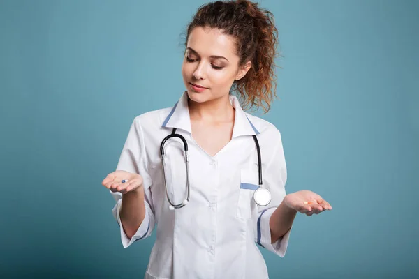 Verpleegkundige vrouw maken van keuze tussen de pillen in haar hand — Stockfoto