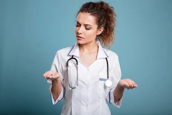 Verpleegkundige vrouw maken van keuze tussen de pillen in haar hand — Stockfoto