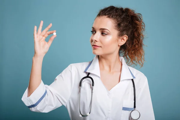 Femme infirmière regardant pilule dans ses doigts — Photo