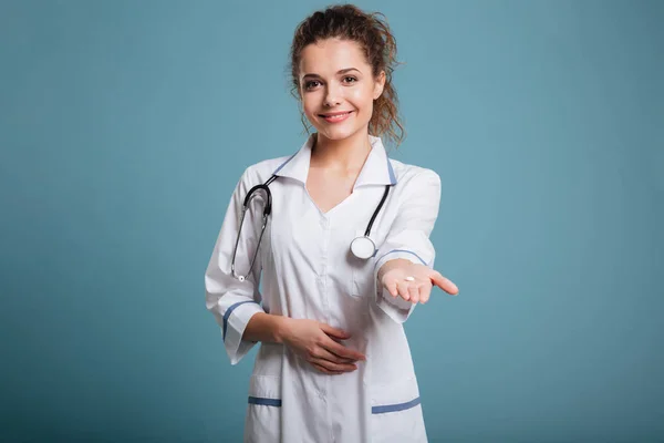 Улыбающаяся медсестра предлагает таблетки в руке — стоковое фото