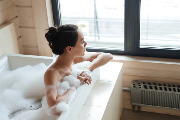 Продумана жінка думає і дивиться на вікно у ванній — стокове фото