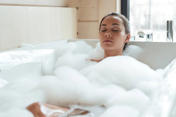 Красива молода жінка з закритими очима відпочиває і розслабляється у ванній — стокове фото