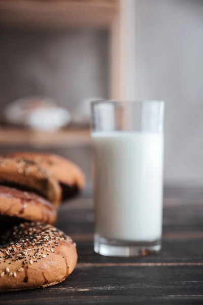 Pečivo a sklenice mléka na tmavý dřevěný stůl — Stock fotografie