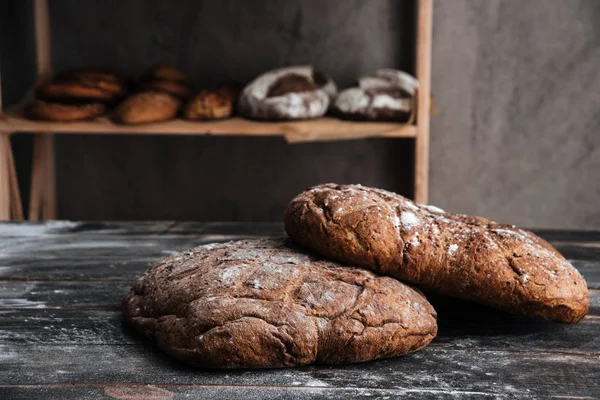 Pain avec farine sur table en bois foncé à la boulangerie — Photo